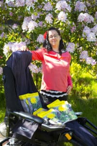 Tina ved siden af kørestol, hvori hendes bog Mælkebøttebarn i Blomst ligger. Fotograf Lars Walther Taknemlig for kærlighed